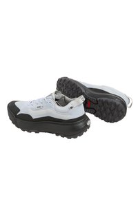 Sneaker bianche e nere con una suola spessa e testurizzata; design snello; superiore in tessuto testurizzato; lacci e linguetta; accenti di branding sul lato.