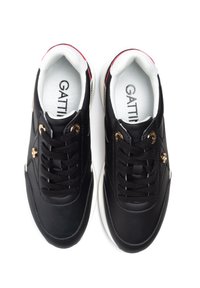 Black sneakers with gold hardware accents, featuring a smooth upper, white lining, and a contrasting sole design. Logo "GATTINI" visible inside.