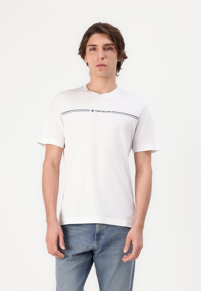 Hvit bomullst-skjorte med rund hals, med en horisontal marineblå stripe og "TOM TAILOR" logo i brysthøyde. Korte ermer.