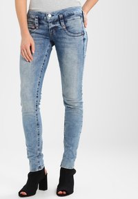 Světlé modré džíny skinny s jemným vyblednutím a mírným zúžením, obsahující pět kapes a stříbrné kovové doplňky.