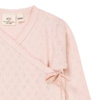 Lys rosa strikket omslagsgenser med teksturert hjerte mønster, bølgete kanter og sidelukking med knytning. Lappen synlig på kragen.