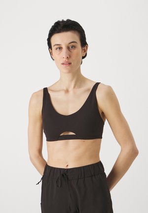 Black sports bra with a rounded neckline and wide straps, featuring a front cut-out detail. Soft, stretchy fabric provides a smooth texture.