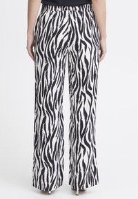 Svartvit zebra-mönstrad vida byxor med elastisk midja, mjuk textur och hel längd med en avslappnad passform.