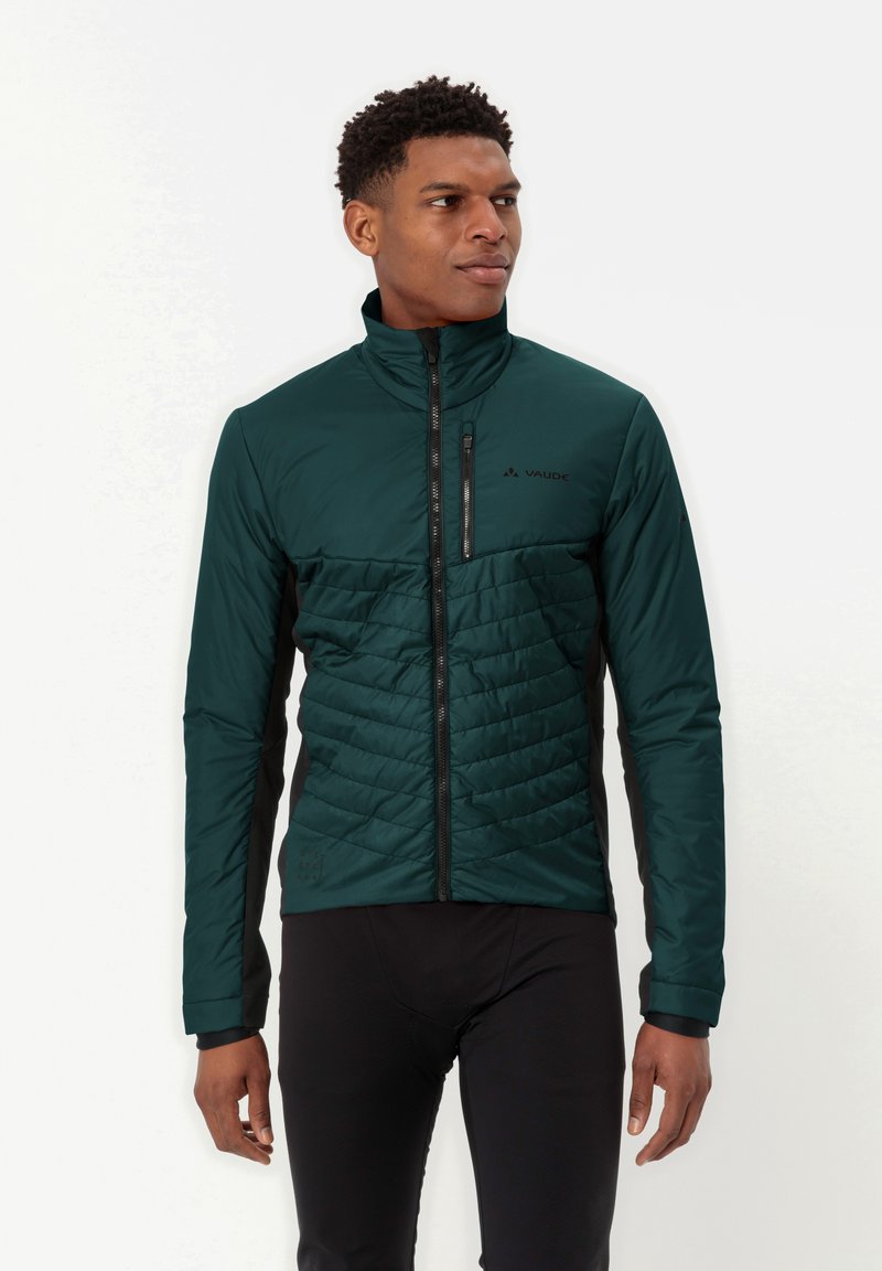 Giacca imbottita verde scuro con collo alto, pannelli laterali neri e zip frontale completa. Presenta una texture trapuntata nella zona del petto.