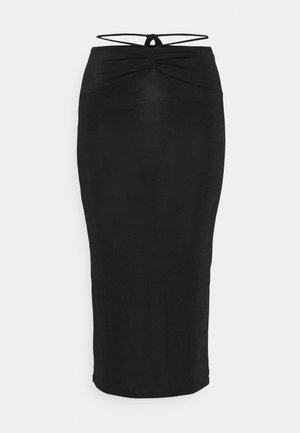 Jupe midi noire taille haute avec fronces sur le devant et fines lanières à nouer autour de la taille sur fond blanc.