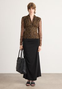 Duga crna suknja u kombinaciji s prozirnom bluzom s leopard uzorkom. Istaknuta crna torba s cik-cak uzorkom i ravne crne sandale.