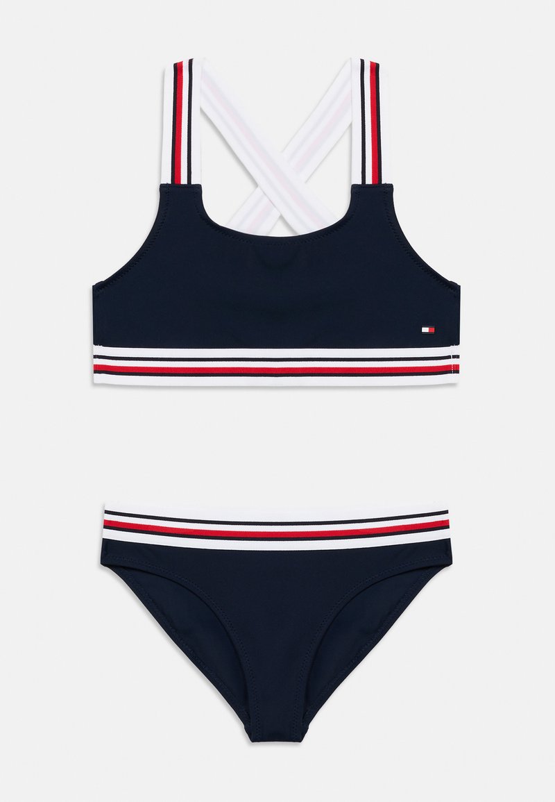 Σετ μπικίνι σε ναυτικό μπλε χρώμα με τοπ διασταυρούμενης πλάτης που έχει λευκές και κόκκινες ρίγες και κάτω μέρος που ταιριάζει με ριγωτή μέση. Κατασκευασμένο από ελαστικό υλικό για κολύμπι.