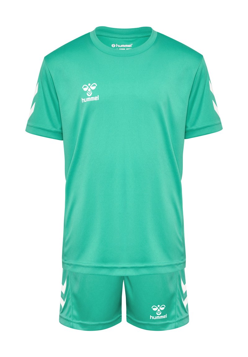 Tenue de sport verte en tissu léger. La chemise à manches courtes et le short présentent un logo blanc et des accents en chevron sur les manches et sur les côtés.