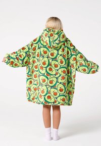 Zaļa oversized kapuces sega. Mīksts materiāls ar atkārtotu avokado un pīļu rakstu. Lieli piedurkņu izvietojumi un vaļīgs piegriezums.