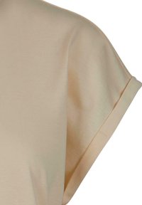 Beige short sleeve with a folded cuff detail on a soft, smooth fabric.