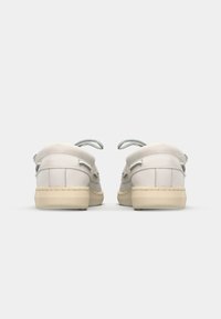 Ljust grå sneakers med en slät ovandel, rund tå och snörningsdesign. Krämfärgade gummisulor med subtila sömdetaljer.