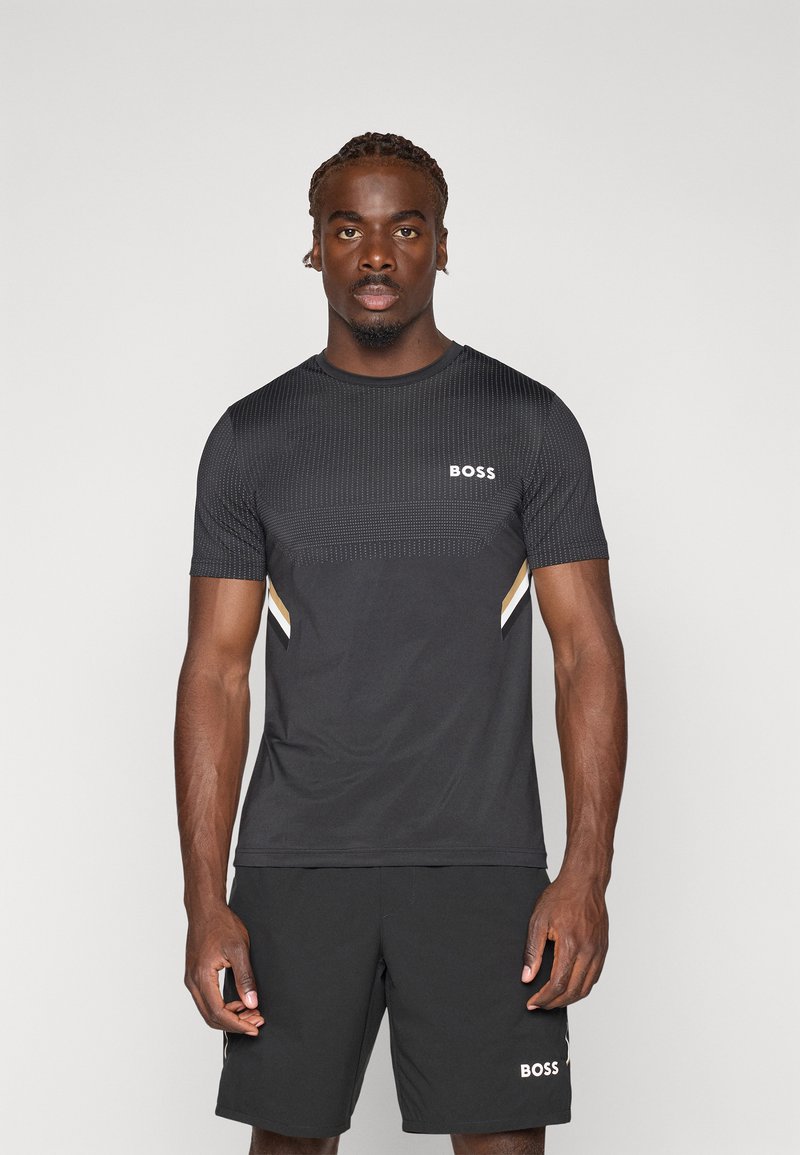 T-shirt de sport noir avec un design texturé, à manches courtes, et un logo sur la poitrine. Associé à un short noir uni.