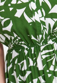 Grünes Kleid mit einem weißen abstrakten Muster, gerafftem Bund mit Gummi, weichem Material und fließender Textur.