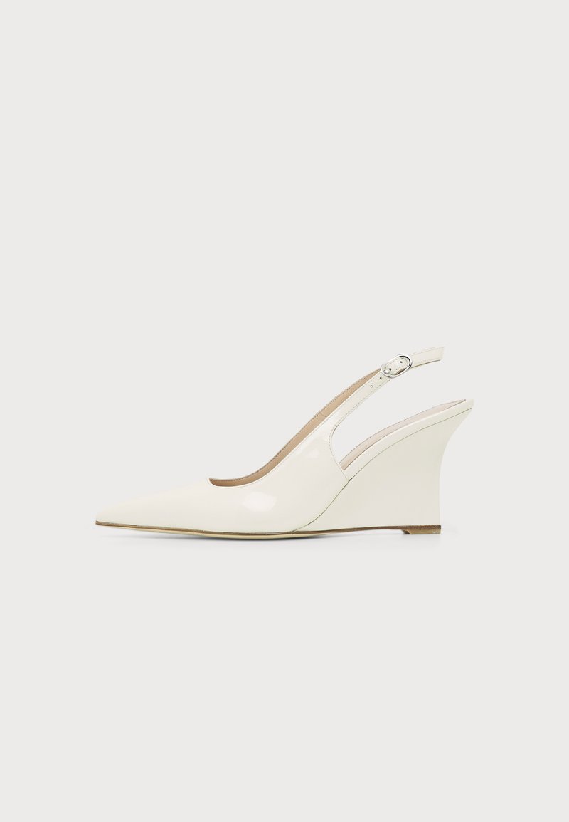 Chaussure compensée blanche en cuir verni avec bout pointu et bride ajustable à boucle sur fond uni.