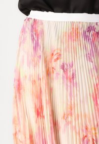 Faltenrock mit fließendem Design aus leichtem Stoff, mit einem floralen Muster in pastellrosa, orange und lila Tönen. Der Bund ist weiß.
