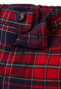 Tessuto a quadri rosso e blu navy con chiusura a bottone, morbido al tatto, e un pattern a scacchi contrastante, con una piega nella parte superiore.