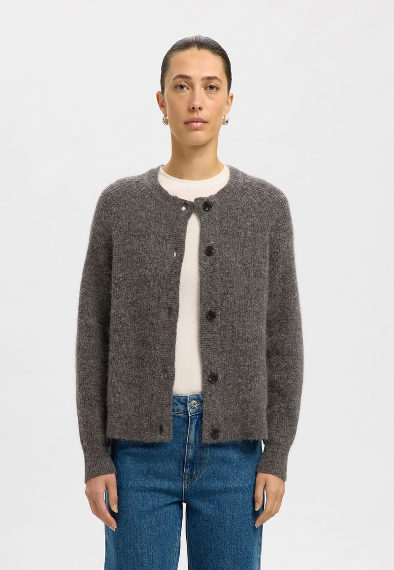 Grijze, zachte cardigan van textuurstof, met een ronde halslijn, knopen aan de voorkant en geribde manchetten, gedragen over een witte top.