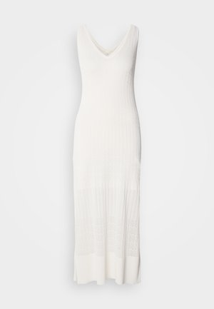 Biała, bez rękawów, dziana sukienka z dekoltem w kształcie litery V, o prążkowanej fakturze i długości poniżej kolan z wzorzystą dolną częścią.
