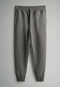Szare spodnie dresowe z elastycznym pasem, sznurkiem do regulacji i elastycznymi ściągaczami na końcach nogawek. Posiadają dwie boczne kieszenie oraz gładką, miękką fakturę.
