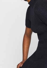 Abito a maniche corte in maglia blu scuro con una trama a spina di pesce testurizzata, che presenta una silhouette aderente e un collo alto.