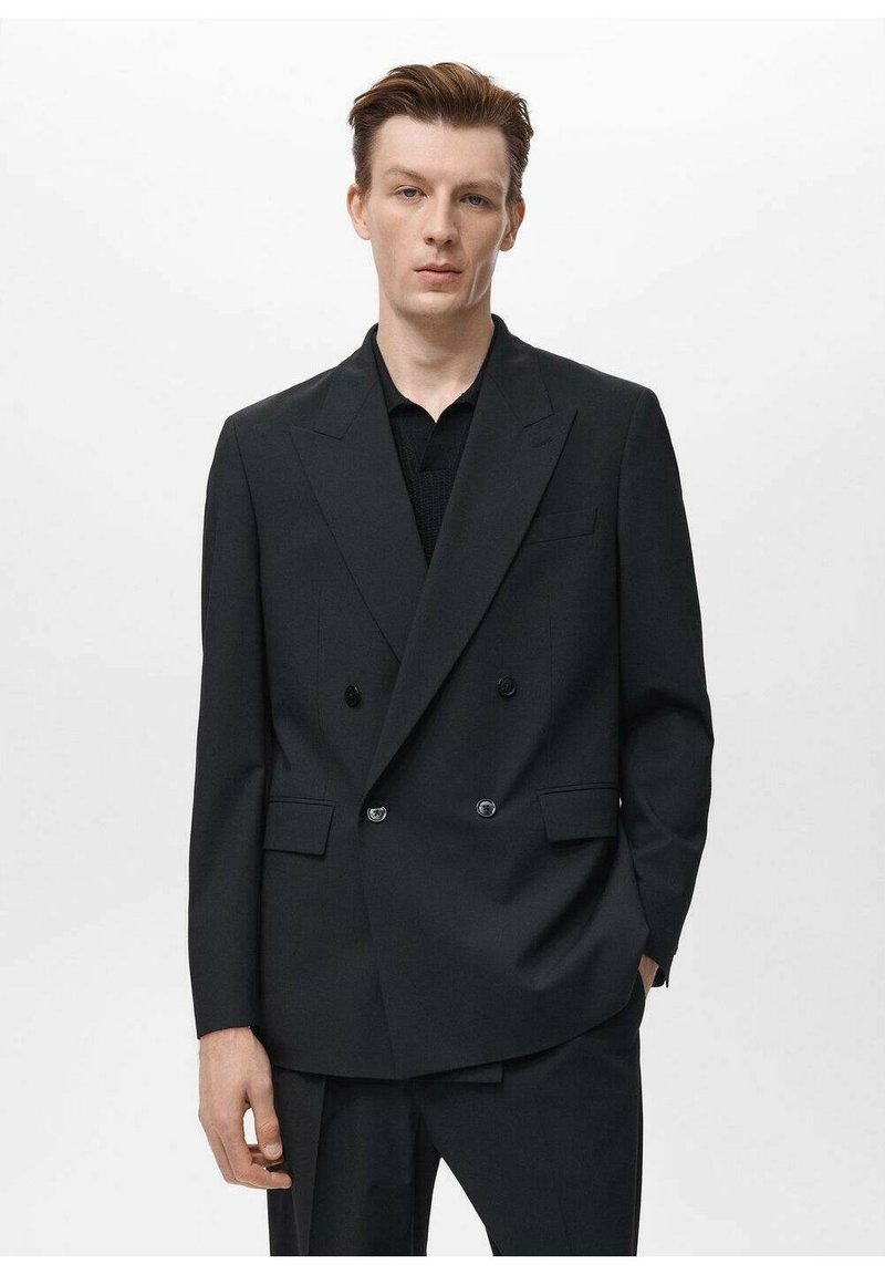 Black double-breasted blazer made from smooth fabric. Features wide lapels, two front pockets, and shiny buttons. Textured black shirt underneath.