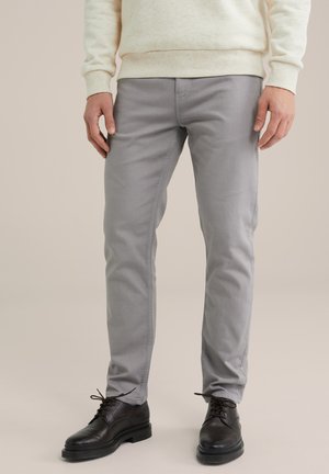 Chino grigi con un design slim fit, realizzati in un morbido misto cotone. Indossati con scarpe in pelle nera e un maglione color crema chiaro.