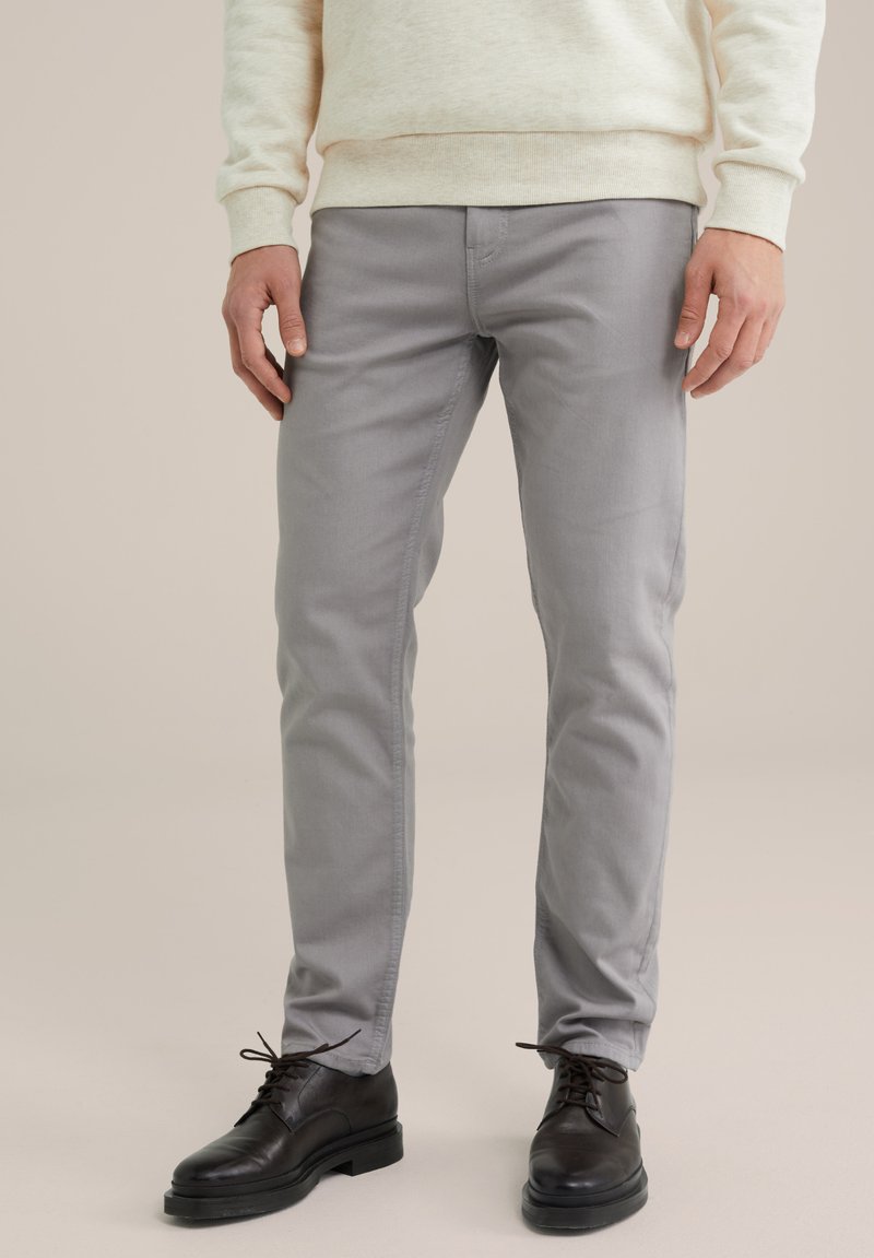 Gray chinos with a slim fit design, made from a smooth cotton blend. Worn with black leather shoes and a light cream sweater.