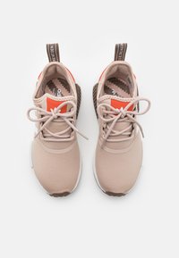 Beige träningsskor med orange accenter, som har en slät tygövre del, rund tå, snörningsdesign och en texturerad brun sula.