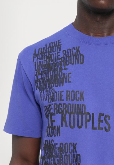Purple cotton t-shirt featuring black graphic text in varying fonts and sizes, with words like "LOVE," "INDIE ROCK," and "UNDERGROUND."