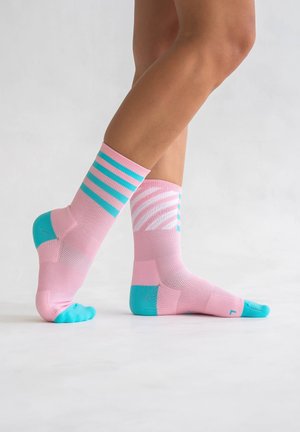 Rosa Sportsocken mit türkisfarbenen Akzenten. Eine Socke hat horizontale Streifen, während die andere ein Zickzackmuster aufweist. Strukturiertes Material.