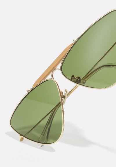 Green, triangular sunglasses with gold metal frame and beige accents. Features include integrated nose pads and a sleek design.