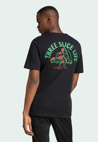 T-shirt nera con una grafica colorata sul retro con testo verde, che raffigura tre fette di pizza con condimenti e dettagli che gocciolano.