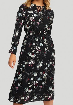 Robe noire à fleurs avec des manches longues, taille froncée et un lien au cou. Présente des fleurs colorées dans des tons de bleu, rose et blanc sur un fond sombre.