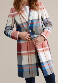 Lang geruite jas met een mix van rode, blauwe, witte en beige kleuren. Dubbelzijdig ontwerp met twee knopen en een geknipt kraag.