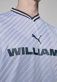 Biała sportowa koszulka wykonana z siateczkowego materiału z poziomymi paskami. Posiada czarny dekolt w kształcie litery V oraz wyraźny napis "WILLIAM" z przodu.