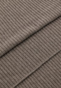 Brun ribbet strikstof, der viser en blød tekstur med et ensartet mønster på tværs af tre overlappende lag.