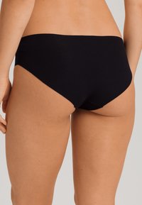 Slip in cotone nero con una texture liscia e un design minimalista, caratterizzato da un taglio a vita bassa e bordi senza cuciture per il massimo comfort.
