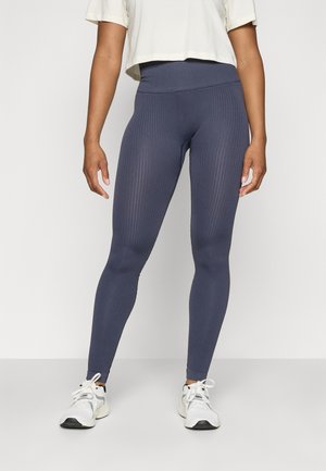 Leggings a coste navy realizzati in materiale elastico, caratterizzati da una vita alta e un design aderente. Abbinati a scarpe da ginnastica bianche.