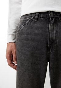 Jeans de mezclilla gris con corte recto, con una cintura baja, diseño de cinco bolsillos y un ligero desgaste. Cierre con botón y cremallera.
