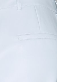 Světlomodré kalhoty z umělé kůže s hladkým povrchem, se zadní kapsou a prošitím podél pasu a švů.