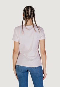 Lichtroze katoenen T-shirt met korte mouwen, aansluitend ontwerp en een ronde halslijn, gecombineerd met blauwe denimjeans.