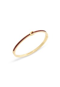 Bracciale in metallo dorato con un design sottile, caratterizzato da una striscia in smalto rosso e un accento circolare. Logo inciso vicino alla chiusura.