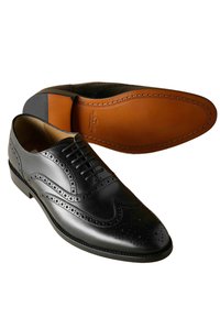 Pantofi de dress din piele neagră, cu detalii brogue, un vârf rotund și o suprafață netedă. Talpa este de o culoare bej contrastantă, cu cusături.