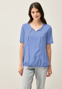 Blusa blu a maniche corte con scollatura a V, dettaglio con cordoncino e orlo inferiore elastico. Tessuto morbido e leggero.