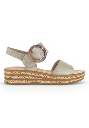 Sandale compensée en suede beige avec deux brides avant et une bride latérale à la cheville, dotée d'une grande boucle ronde et d'une semelle en liège superposée.