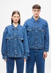 Traper jakne svijetlo plave boje s teksturiranim uzorkom. Obje imaju kopčanje na gumbe, dva prednja džepa i opušteni kroj.