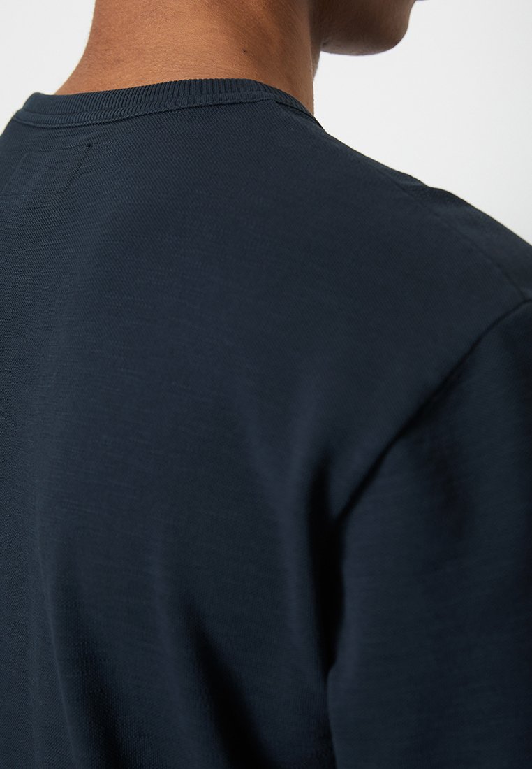 Granatowa bawełniana koszulka z okrągłym dekoltem i krótkimi rękawami, o gładkiej fakturze i minimalistycznym designie.