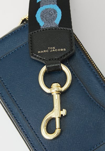 Jūrinio tono tekstūruotas maišelis su auksinėmis detalėmis. Pavaizduota prekės ženklo pavadinimas 'The Marc Jacobs' juodoje juostoje su mėlynomis dizaino akcentais.