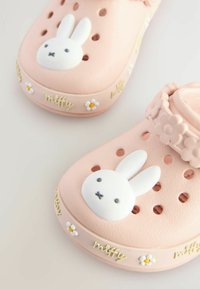 Lyserøde klipklapper med et hvidt kaninansigt, blomsterdekorationer og udskårne ventilationshuller. Tekstureret gummimateriale med "miffy" branding.
