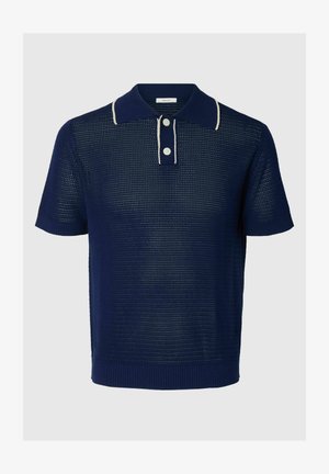 Polo en maille bleu marine à manches courtes avec bordure blanche au col et deux boutons blancs sur la patte de boutonnage.